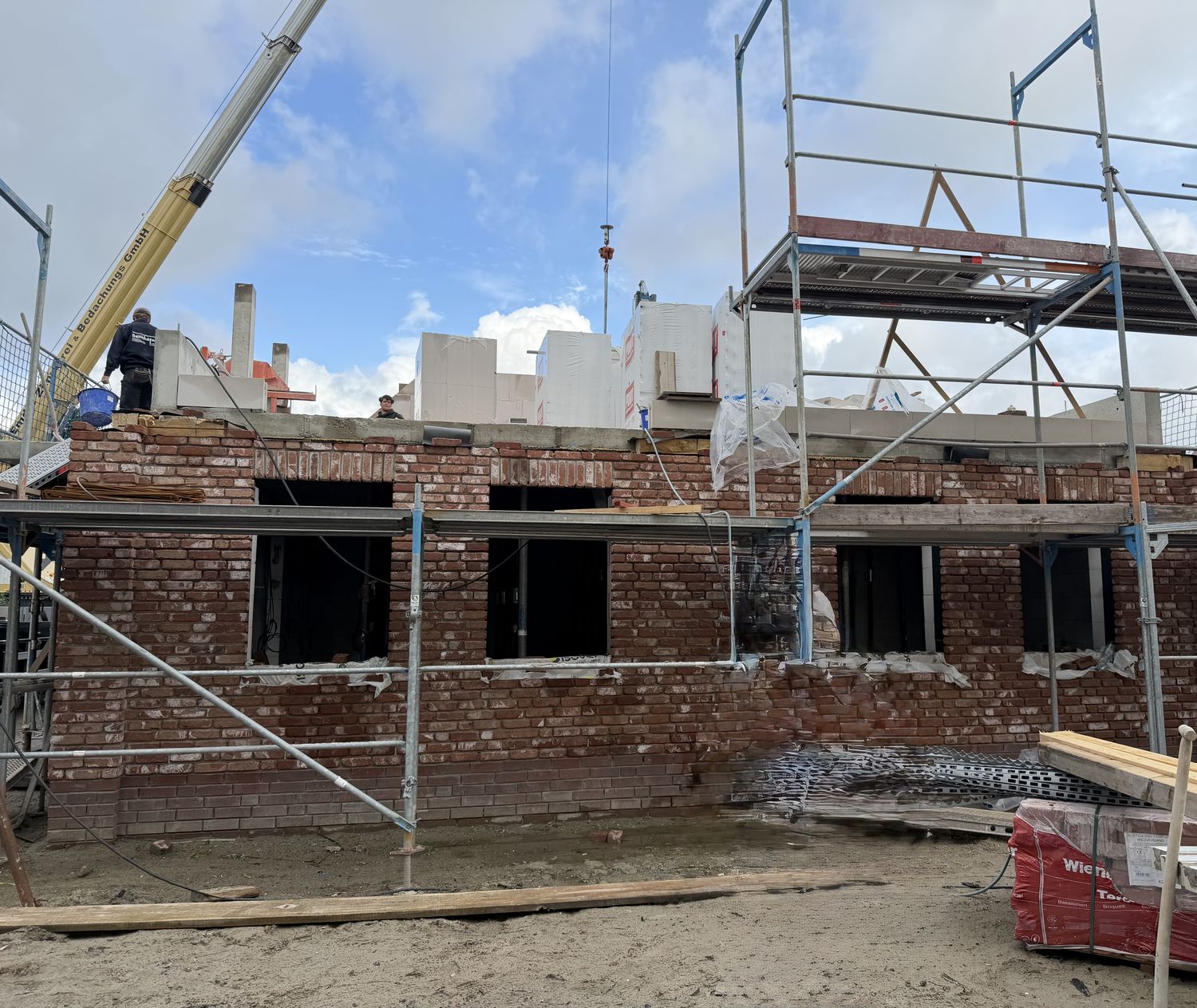 Klinkerfassade des Küstenquartiers im Rohbau mit Gerüst, darüber die Wände des Obergeschosses
